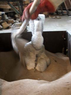 Hot molds set in sand Glowing hot ceramic shell molds are quickly set in sand prior to pouring the bronze